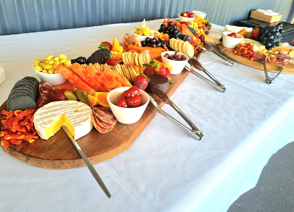 Elegant grazing boards with cured meats, cheese and fresh produce on white tablecloth linen for a catered gathering