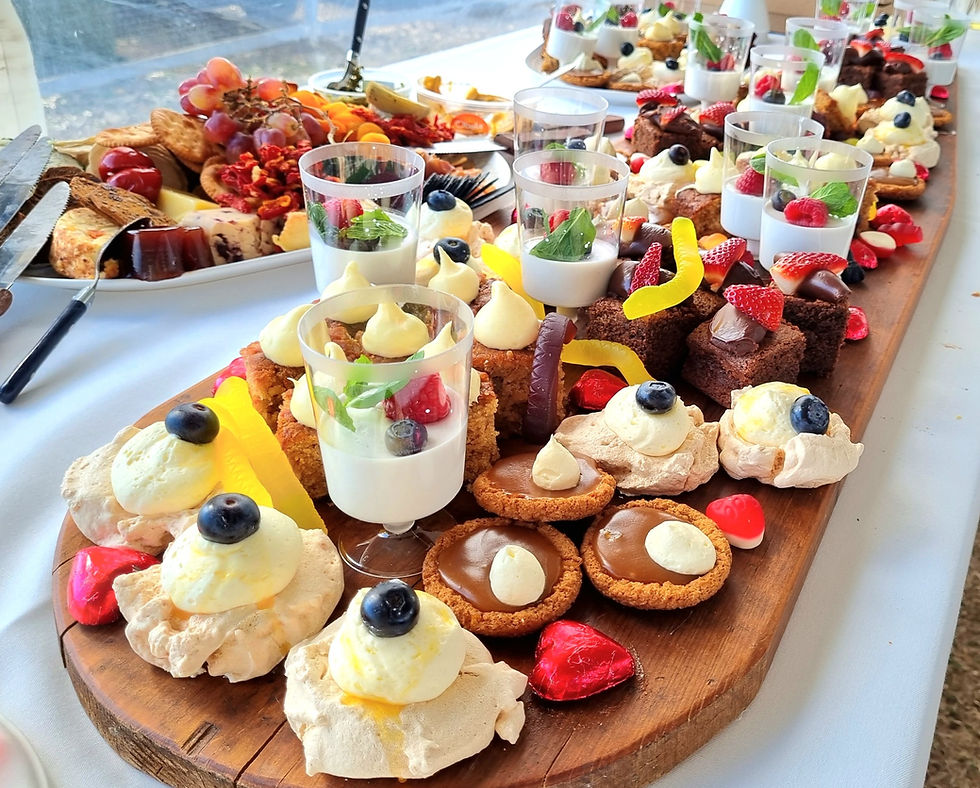Abundant dessert grazing board with pavlovas, chocolate brownies, caramel tarts and fresh fruit for a festive event
