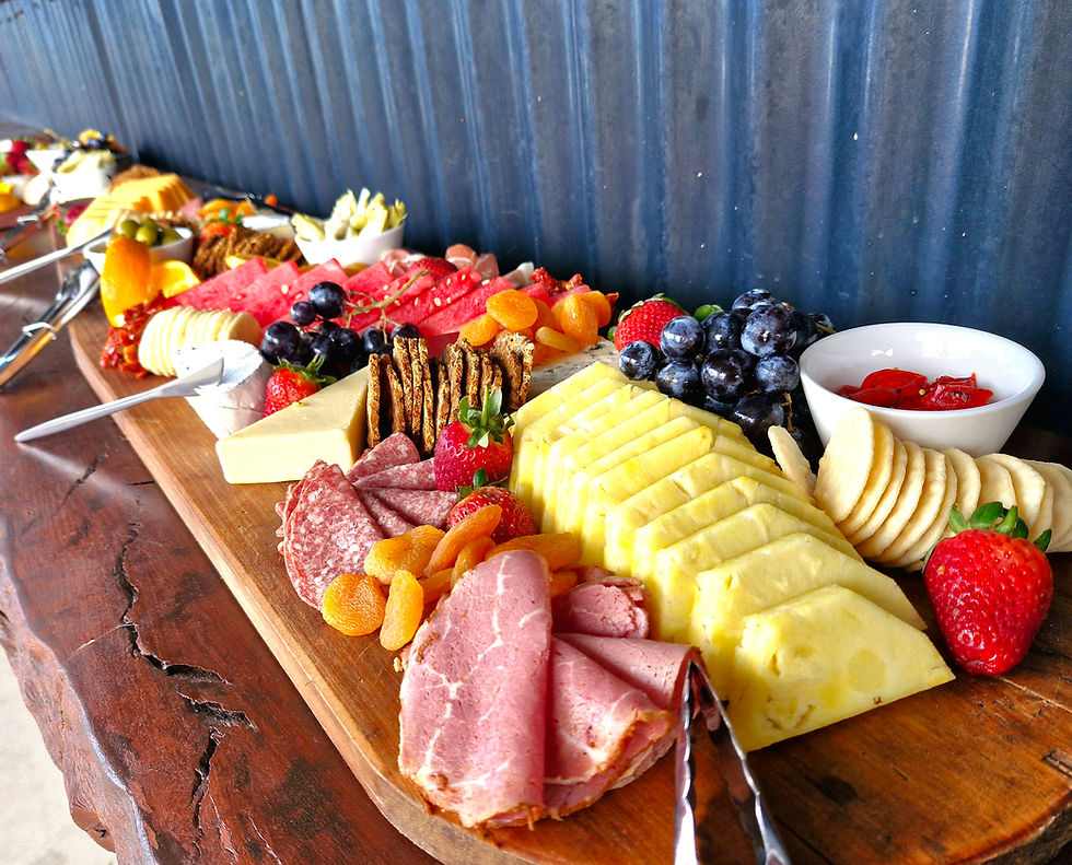 Long rustic grazing board loaded with cured meats, cheese, fresh fruit and crackers for a shared table event